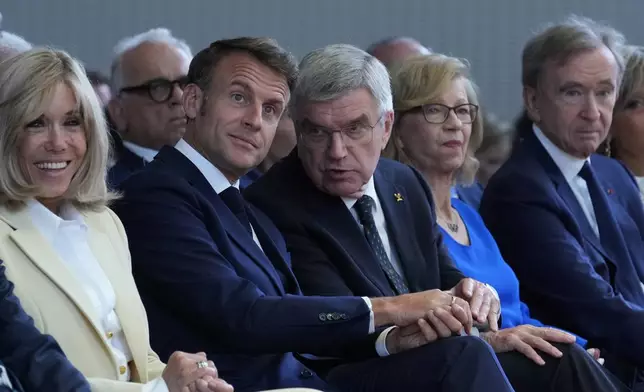 IOC President Thomas Bach, center, French President Emmanuel Macron, center left, his wife Brigitte Macron, left, and LVMH CEO Bernard Arnault, right, sit, during the IOC Session Opening Ceremony at the Louis Vuitton Foundation ahead of the 2024 Summer Olympics, Monday, July 22, 2024, in Paris, France. (AP Photo/Thibault Camus)