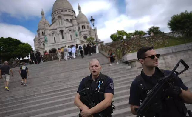 Officers from the National Police Intervention Force stand watch outside Sacre Coeur of Montmartre Basilica, ahead of the 2024 Summer Olympics, Monday, July 22, 2024, in Paris, France. (AP Photo/Rebecca Blackwell)