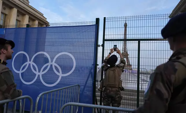 A. Soldier takes a photo of the Eiffel Tower as he patrols at the Trocadero plaza Thursday, July 18, 2024 in Paris. (AP Photo/David Goldman)