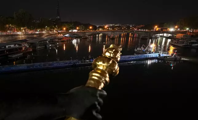 Technicians remove the pontoon for the start of the triathlon events after the event was postponed over concerns about water quality in Paris' Seine River, at the 2024 Summer Olympics, Tuesday, July 30, 2024, at the Pont Alexandre III bridge in Paris, France. (AP Photo/Vadim Ghirda)