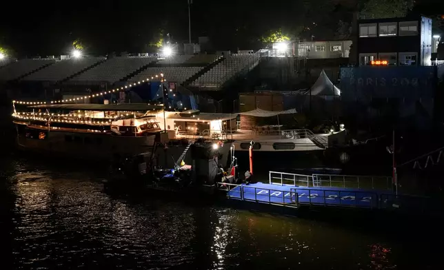 Technicians remove the pontoon for the start of the triathlon events after the event was postponed over concerns about water quality in Paris' Seine River, at the 2024 Summer Olympics, Tuesday, July 30, 2024, at the Pont Alexandre III bridge in Paris, France. (AP Photo/Yasin Dar)