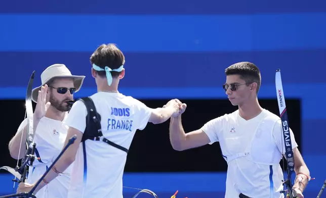 France's Thomas Chirault, right, Jean-Charles Valladont, left, and Baptiste Addis celebrate a win during the men's team quarterfinals Archery competition against Italy at the 2024 Summer Olympics, Monday, July 29, 2024, in Paris, France. (AP Photo/Rebecca Blackwell)