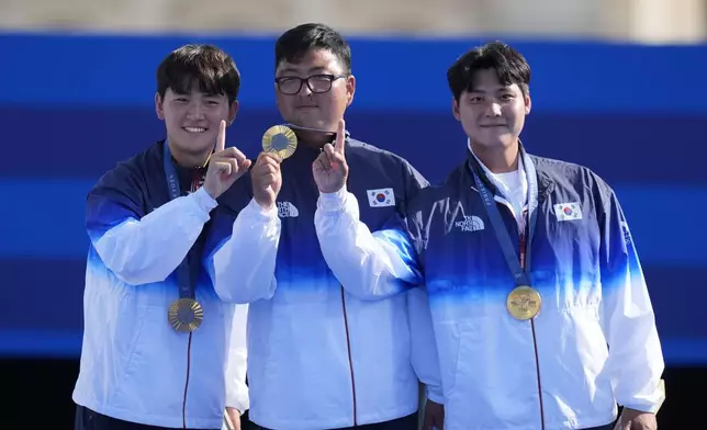 Gold medal winners, South Korea's Je Deok Kim, left, Woojin Kim, center, Wooseok Lee, right, celebrate during the men's team medal ceremony at the 2024 Summer Olympics, Monday, July 29, 2024, in Paris, France. (AP Photo/Rebecca Blackwell)