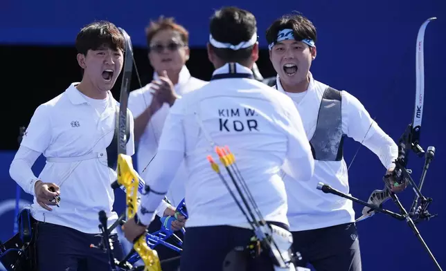 South Korea's Wooseok Lee, right, South Korea's Je Deok Kim, left, and South Korea's Woojin Kim, center celebrate after a win during the men's team gold medal match Archery competition against France at the 2024 Summer Olympics, Monday, July 29, 2024, in Paris, France. (AP Photo/Rebecca Blackwell)