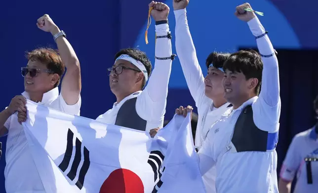 South Korea's Woojin Kim, center, Wooseok Lee, and Je Deok Kim celebrate after a win during the men's team gold medal match Archery competition against France at the 2024 Summer Olympics, Monday, July 29, 2024, in Paris, France. (AP Photo/Rebecca Blackwell)