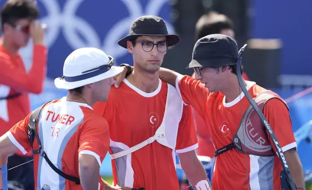 Turkey's Berkim Tumer, left, Abdullah Yildirmis, center and Mete Gazoz gather during the men's team bronze medal Archery competition against at the 2024 Summer Olympics, Monday, July 29, 2024, in Paris, France. (AP Photo/Rebecca Blackwell)