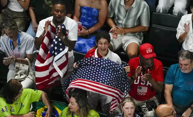 Simone Biles, of United States, husband Jonathon Owens along with her mother and farher Ron and Nellie Biles cheer as she is introduced during the women's artistic gymnastics team finals at the 2024 Summer Olympics, Tuesday, July 30, 2024, in Paris, France. (AP Photo/Morry Gash)