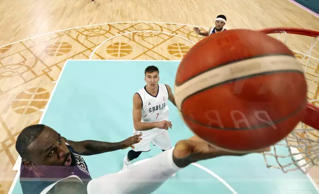 LeBron James, left, of the United States, shoots as Bogdan Bogdanovic, of Serbia, during a men's basketball game at the 2024 Summer Olympics, Sunday, July 28, 2024, in Villeneuve-d'Ascq, France. (Gregory Shamus/Pool Photo via AP)