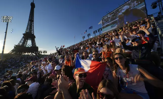 French spectators at Eiffel Tower Stadium watch beach volleyball at sunset at the 2024 Summer Olympics, Sunday, July 28, 2024, in Paris, France. (AP Photo/Robert F. Bukaty)