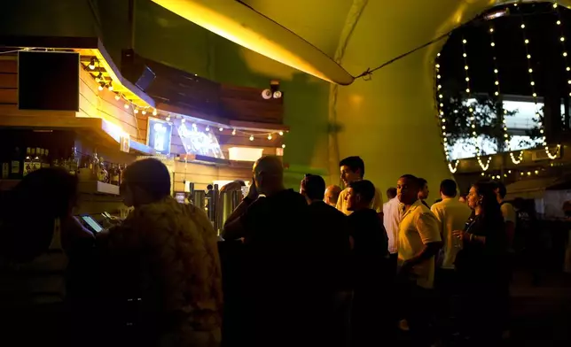 People stand at a bar during the DiscOlympics at Wanderlust night club at the 2024 Summer Olympics, Monday, July 29, 2024, in Paris, France. The legendary French disco artist Cerrone played at the DiscOlympics which paid homage to the root of dance music. (AP Photo/Natacha Pisarenko)