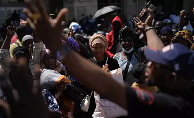 People gesture during a migrants' protest at the 2024 Summer Olympics, Thursday, July 25, 2024, in Paris, France. On the eve of the grandiose opening ceremony for the Paris Olympics, police cleared out migrants sleeping in a tent camp in the capital as social and environmental advocacy groups raise attention to criticisms of the Paris Games such as the displacement of migrants and housing issues. (AP Photo/David Goldman)