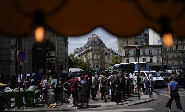 Migrants protest in front of an official at the 2024 Summer Olympics, Thursday, July 25, 2024, in Paris, France. On the eve of the grandiose opening ceremony for the Paris Olympics, police cleared out migrants sleeping in a tent camp in the capital as social and environmental advocacy groups raise attention to criticisms of the Paris Games such as the displacement of migrants and housing issues. (AP Photo/David Goldman)