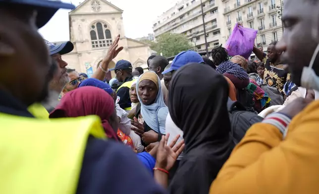 Migrants react before boarding buses at the 2024 Summer Olympics, Thursday, July 25, 2024, in Paris, France. On the eve of the grandiose opening ceremony for the Paris Olympics, police cleared out migrants sleeping in a tent camp in the capital as social and environmental advocacy groups raise attention to criticisms of the Paris Games such as the displacement of migrants and housing issues. (AP Photo/David Goldman)