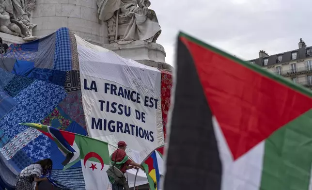 A banner is unfurled reading "France is made of migrations," in Republique plaza during a demonstration by several associations for what they called the "Counter Opening Ceremony" against the 2024 Summer Olympics, Thursday, July 25, 2024, in Paris. Demonstrators gave speeches about the cost of the Olympic Games and said authorities have been using the Games as a pretext for what they call social cleansing, by removing migrants and homeless people off the streets in order to preserve a picture-postcard image of the city for the millions of visitors coming. (AP Photo/David Goldman)