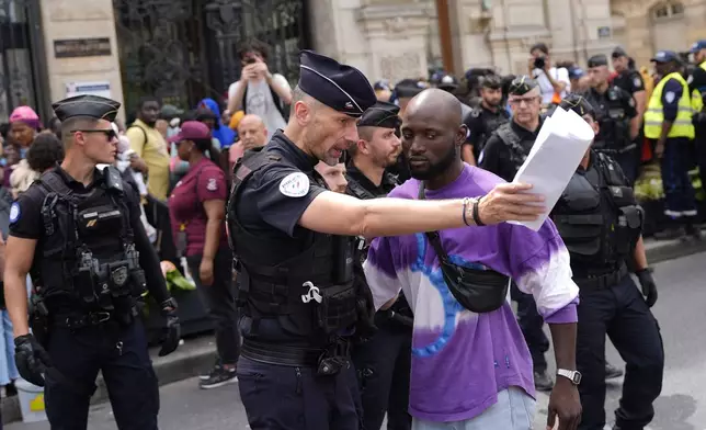 Police officers escort away man during a migrants' protest at the 2024 Summer Olympics, Thursday, July 25, 2024, in Paris, France. On the eve of the grandiose opening ceremony for the Paris Olympics, police cleared out migrants sleeping in a tent camp in the capital as social and environmental advocacy groups raise attention to criticisms of the Paris Games such as the displacement of migrants and housing issues. (AP Photo/David Goldman)