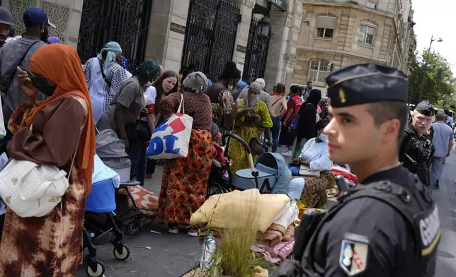 Police officers secure the area during a migrants' protest at the 2024 Summer Olympics, Thursday, July 25, 2024, in Paris, France. On the eve of the grandiose opening ceremony for the Paris Olympics, police cleared out migrants sleeping in a tent camp in the capital as social and environmental advocacy groups raise attention to criticisms of the Paris Games such as the displacement of migrants and housing issues. (AP Photo/David Goldman)