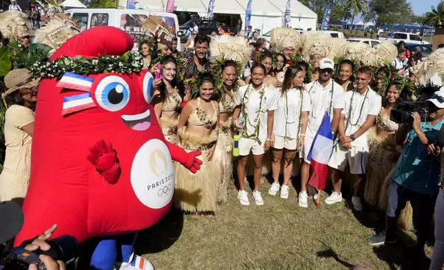 The surfing team from France stand with dancers and the mascot during an opening ceremony for the 2024 Summer Olympics surfing competition Friday, July 26, 2024, in Papara, Tahiti. (AP Photo/Gregory Bull)