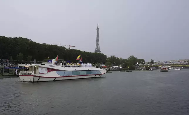 A parade of boats moves down the Seine River as the Eiffel Tower is seen in the distance in Paris, France, during the opening ceremony of the 2024 Summer Olympics, Friday, July 26, 2024. (AP Photo/Morry Gash, Pool)