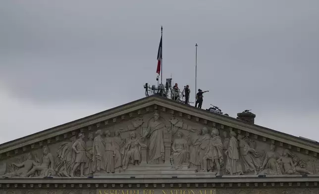 Security staff stand atop the roof of the National Assembly in Paris, France, ahead of the opening ceremony of the 2024 Summer Olympics, Friday, July 26, 2024. (AP Photo/Charlie Riedel)