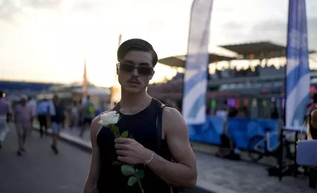 Robin Labarrere holds a flower after performing at the opening of Pride House, the safe space for the LGBT+ community of athletes, during the 2024 Summer Olympics, Monday, July 29, 2024, in Paris, France. (AP Photo/Natacha Pisarenko)