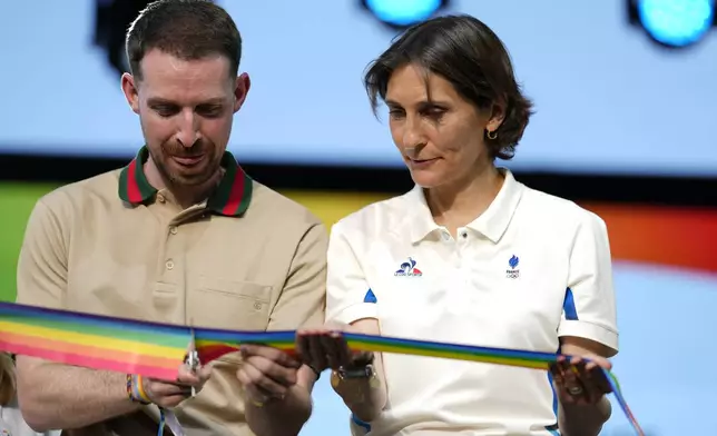 French sports minister Amelie Oudea-Castera, right, and Jeremy Goupille cut the ribbon at the opening of Pride House, the safe space for the LGBT+ community of athletes, during the 2024 Summer Olympics, Monday, July 29, 2024, in Paris, France. (AP Photo/Natacha Pisarenko)