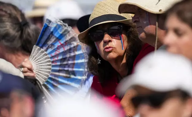 A fan tries to cool off during rowing competitions at the 2024 Summer Olympics, Monday, July 29, 2024, in Vaires-sur-Marne, France. (AP Photo/Lindsey Wasson)