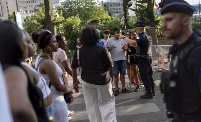 Police give directions to members of the public stopped from entering a security perimeter near the Eiffel Tower ahead of the 2024 Summer Olympics, Saturday, July 20, 2024, in Paris. (AP Photo/David Goldman)