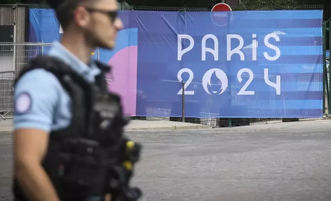 A police officer walks past a Paris olympics canvas at the 2024 Summer Olympics, Saturday, July 20, 2024, in Paris, France. (AP Photo/Thomas Padilla)