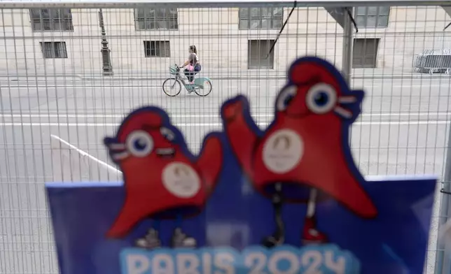 A cyclist rides in an empty street outside the security perimeter set up for the Olympic Games, Thursday, July 18, 2024 in Paris. A special kind of iron curtain came down across central Paris on Thursday, with the beginning of an Olympic anti-terrorism perimeter along the banks of the River Seine sealing off a kilometers-long (miles-long) area to Parisians and tourists who hadn't applied in advance for a pass. (AP Photo/David Goldman)