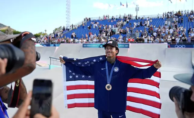 Nyjah Huston, of the United States, poses for photos after winning the bronze medal in the men's skateboard street final at the 2024 Summer Olympics, Monday, July 29, 2024, in Paris, France. (AP Photo/Frank Franklin II)