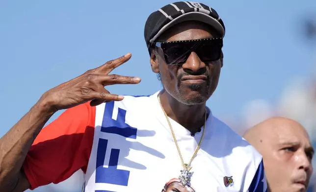 US artist Snoop Dogg gestures to the camera while attending the men's skateboard street final at the 2024 Summer Olympics, Monday, July 29, 2024, in Paris, France. (AP Photo/Frank Franklin II)