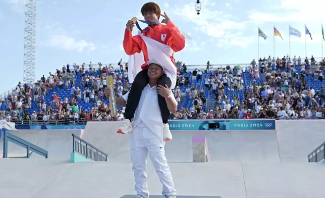 Yuto Horigome, of Japan, celebrates on the shoulders of his coach after winning the gold medal in the men's skateboard street final at the 2024 Summer Olympics, Monday, July 29, 2024, in Paris, France.(AP Photo/Frank Franklin II)