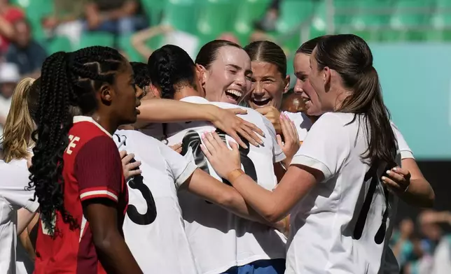 New Zealand's Mackenzie Barry, center, is congratulated after scoring her side's opening goal during the women's Group A soccer match between Canada and New Zealand at Geoffroy-Guichard stadium during the 2024 Summer Olympics, Thursday, July 25, 2024, in Saint-Etienne, France. (AP Photo/Silvia Izquierdo)