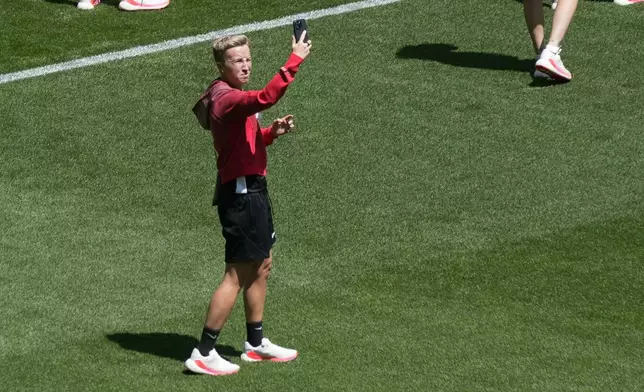 Coach Beverly Priestman of Canada takes photos on the pitch at Geoffroy-Guichard Stadium ahead of the 2024 Summer Olympics, Tuesday, July 23, 2024, in Saint-Etienne, France. Canada is scheduled to play New Zealand on Thursday, July 25. (AP Photo/Silvia Izquierdo)