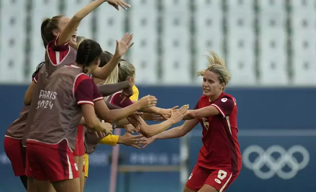 Canada's Cloe Lacasse, right, is congratulated after scoring her side's first goal during the women's Group A soccer match between Canada and New Zealand at Geoffroy-Guichard stadium during the 2024 Summer Olympics, Thursday, July 25, 2024, in Saint-Etienne, France. (AP Photo/Silvia Izquierdo)