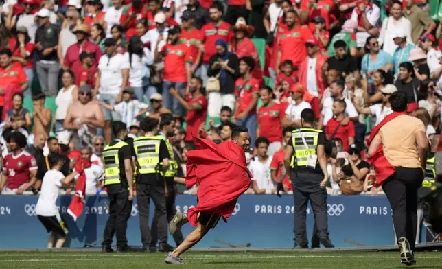 Invaders run on the pitch during the men's Group B soccer match between Argentina and Morocco at Geoffroy-Guichard Stadium at the 2024 Summer Olympics, Wednesday, July 24, 2024, in Saint-Etienne, France. (AP Photo/Silvia Izquierdo)