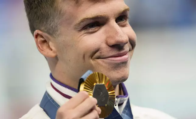 Gold medalist, Leon Marchand, of France, poses after the men's 400-meter individual medley final at the 2024 Summer Olympics, Sunday, July 28, 2024, in Nanterre, France. (AP Photo/Bernat Armangue)