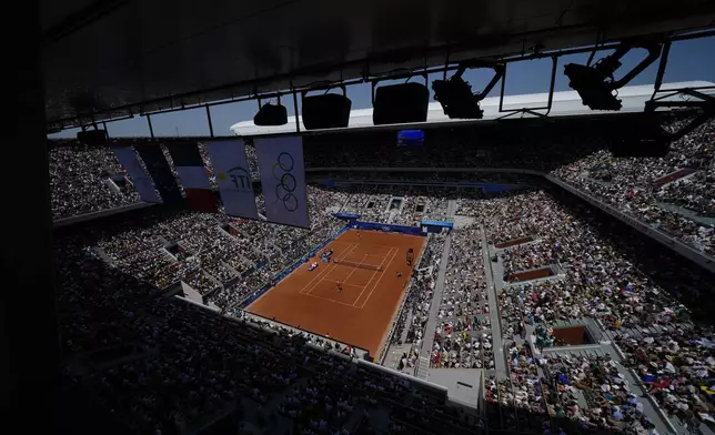 Spectators watch Spain's Rafael Nadal playing Serbia's Novak Djokovic during their men's singles second round match at the 2024 Summer Olympics, Monday, July 29, 2024, at the Roland Garros stadium in Paris, France. (AP Photo/Manu Fernandez)