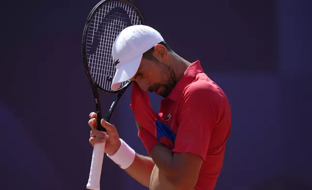 Serbia's Novak Djokovic wipes his face as he plays Spain's Rafael Nadal during their men's singles second round match at the 2024 Summer Olympics, Monday, July 29, 2024, at the Roland Garros stadium in Paris, France. (AP Photo/Andy Wong)