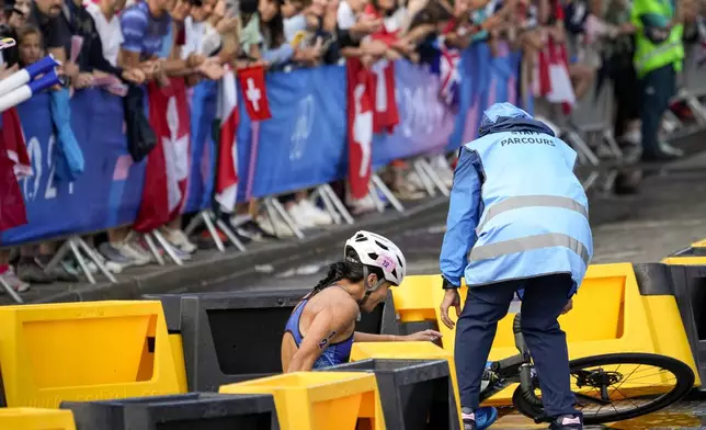 Manami Iijima, of Guam, is helped by staff after crashing during the bike leg of the women's individual triathlon competition at the 2024 Summer Olympics, Wednesday, July 31, 2024, in Paris, France. (AP Photo/David Goldman)