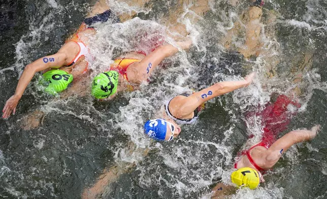 Rachel Klamer, of the Netherlands (50), Spain's Anna Godoy Contreras (43) Germany's Nina Eim (36) and Julie Derron, of Switzerland (7) compete in the swim leg of the women's individual triathlon competition at the 2024 Summer Olympics, Wednesday, July 31, 2024, in Paris, France. (AP Photo/David Goldman)