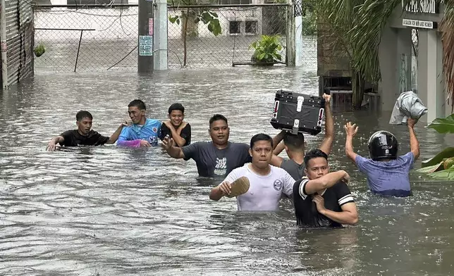 People wade through a flooded street following monsoon rains worsened by offshore typhoon Gaemi on Wednesday, July 24, 2024, in Manila, Philippines. (AP Photo/Joeal Capulitan)