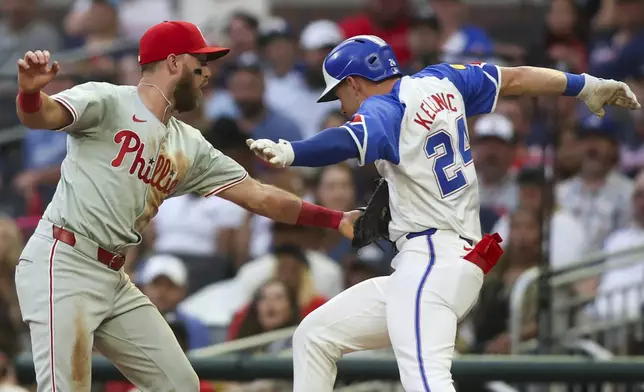 Philadelphia Phillies first baseman Kody Clemens, left, tags out Atlanta Braves' Jarred Kelenic (24) in the third inning of a baseball game Saturday, July 6, 2024, in Atlanta. (AP Photo/Brett Davis)