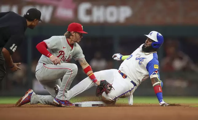 Atlanta Braves' Marcell Ozuna, right, slides safely under the tag of Philadelphia Phillies second baseman Bryson Stott, center, in the fourth inning of a baseball game Saturday, July 6, 2024, in Atlanta. (AP Photo/Brett Davis)