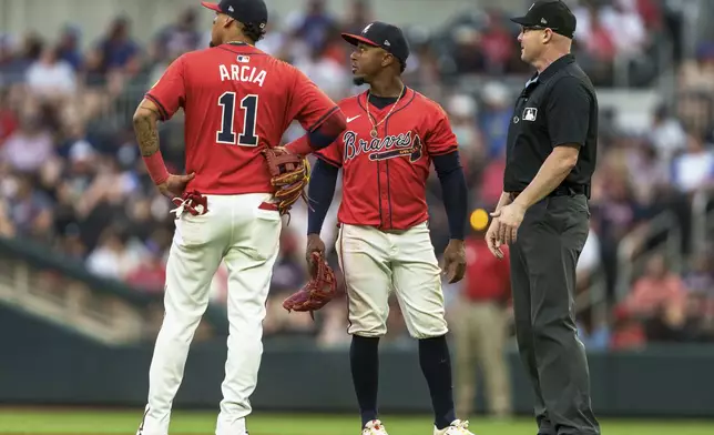 Atlanta Braves shortstop Orlando Arcia (11) and second baseman Ozzie Albies, center, watch an instant replay with umpire Mike Estabrook in the fourth inning of a baseball game against the Philadelphia Phillies, Friday, July 5, 2024, in Atlanta. (AP Photo/Jason Allen)