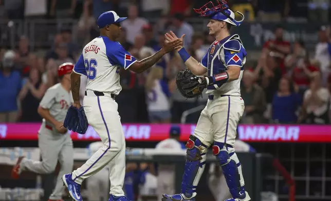 Atlanta Braves relief pitcher Raisel Iglesias (26) celebrates with catcher Sean Murphy, right, after a 5-1 victory over the Philadelphia Phillies in a baseball game, Saturday, July 6, 2024, in Atlanta. (AP Photo/Brett Davis)