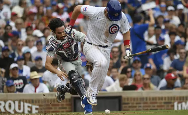 Chicago Cubs' Patrick Wisdom, right, runs to first as Philadelphia Phillies catcher Garrett Stubbs, left, runs down a ground ball before throwing him out at first during the fourth inning of a baseball game Thursday, July 4, 2024, in Chicago. (AP Photo/Paul Beaty)