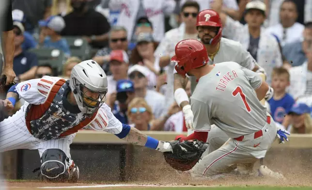 Philadelphia Phillies' Trea Turner (7) slides into home plate safely on a Brandon Marsh single while Chicago Cubs catcher Tomas Nido left, tries to apply the tag during the first inning of a baseball game Thursday, July 4, 2024, in Chicago. (AP Photo/Paul Beaty)