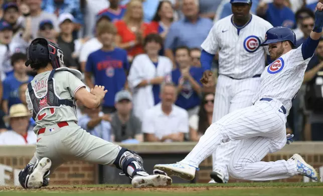 Chicago Cubs' Ian Happ,, right, slides toward home plate before being tagged out by Philadelphia Phillies catcher Garrett Stubbs, left, during the seventh inning of a baseball game Thursday, July 4, 2024, in Chicago. (AP Photo/Paul Beaty)