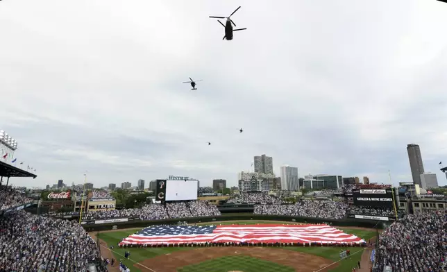 Helicopters fly over Wrigley Field during a Fourth of July tribute before a baseball game between the Chicago Cubs and Philadelphia Phillies Thursday, July 4, 2024, in Chicago. (AP Photo/Paul Beaty)